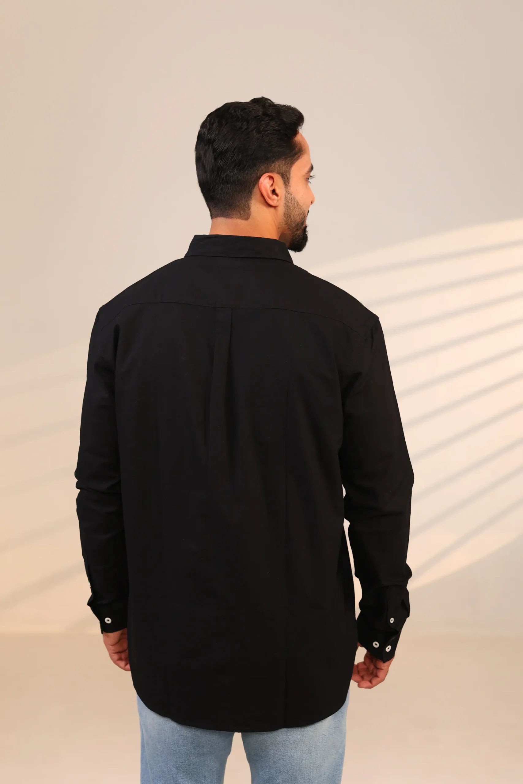 Rear view of man in black shirt under soft lighting.
