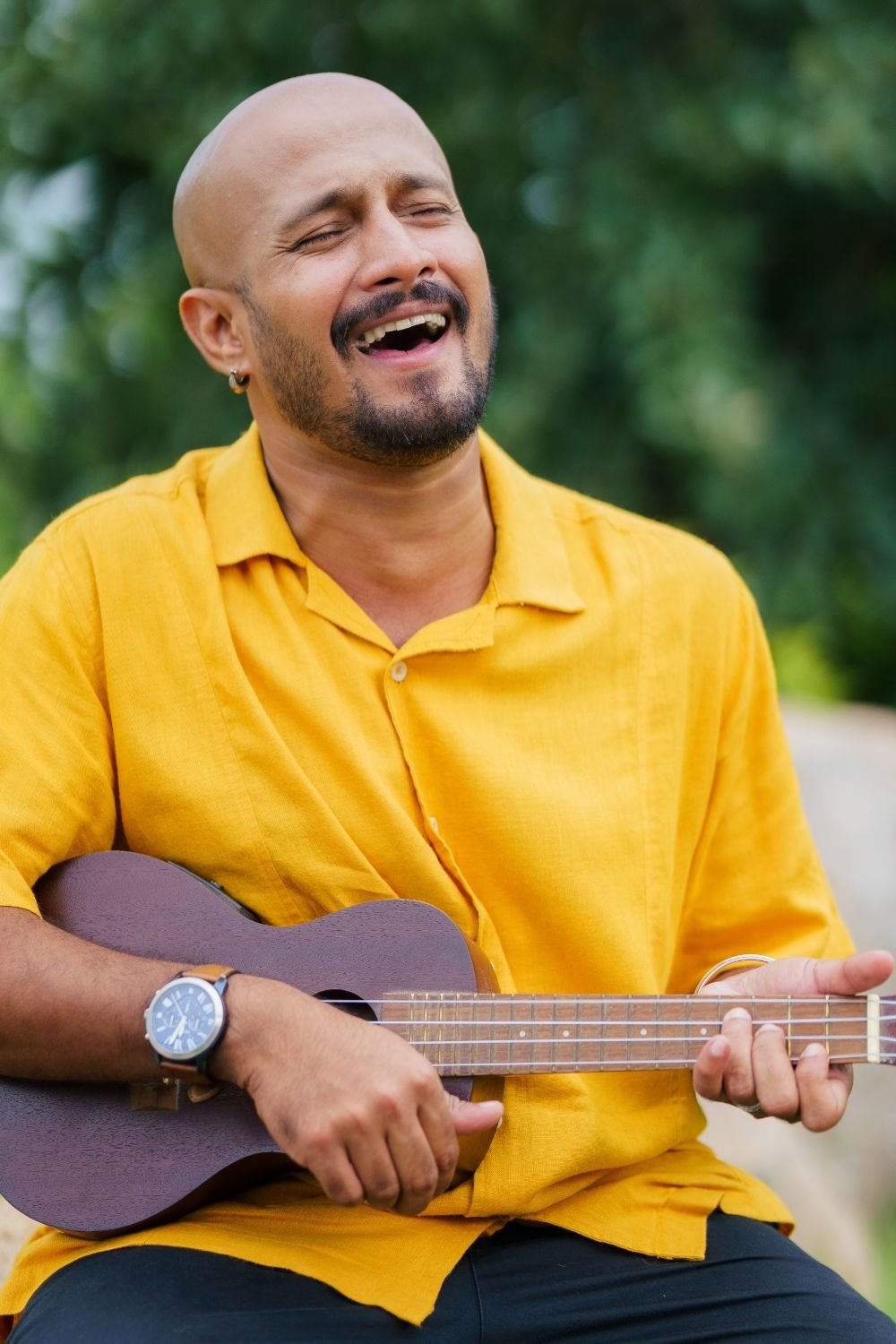 Smiling man playing ukulele in yellow shirt