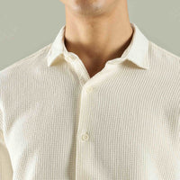 Close-up of a person wearing a textured beige shirt against a neutral background