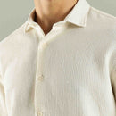 Close-up of a person wearing a textured beige shirt with a neutral background