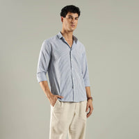 Man wearing a light blue striped shirt and beige pants against a gray background