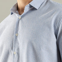 Close-up of a person wearing a blue and white striped shirt with a neutral background