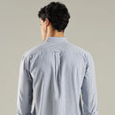 Man wearing a blue striped shirt against a beige background