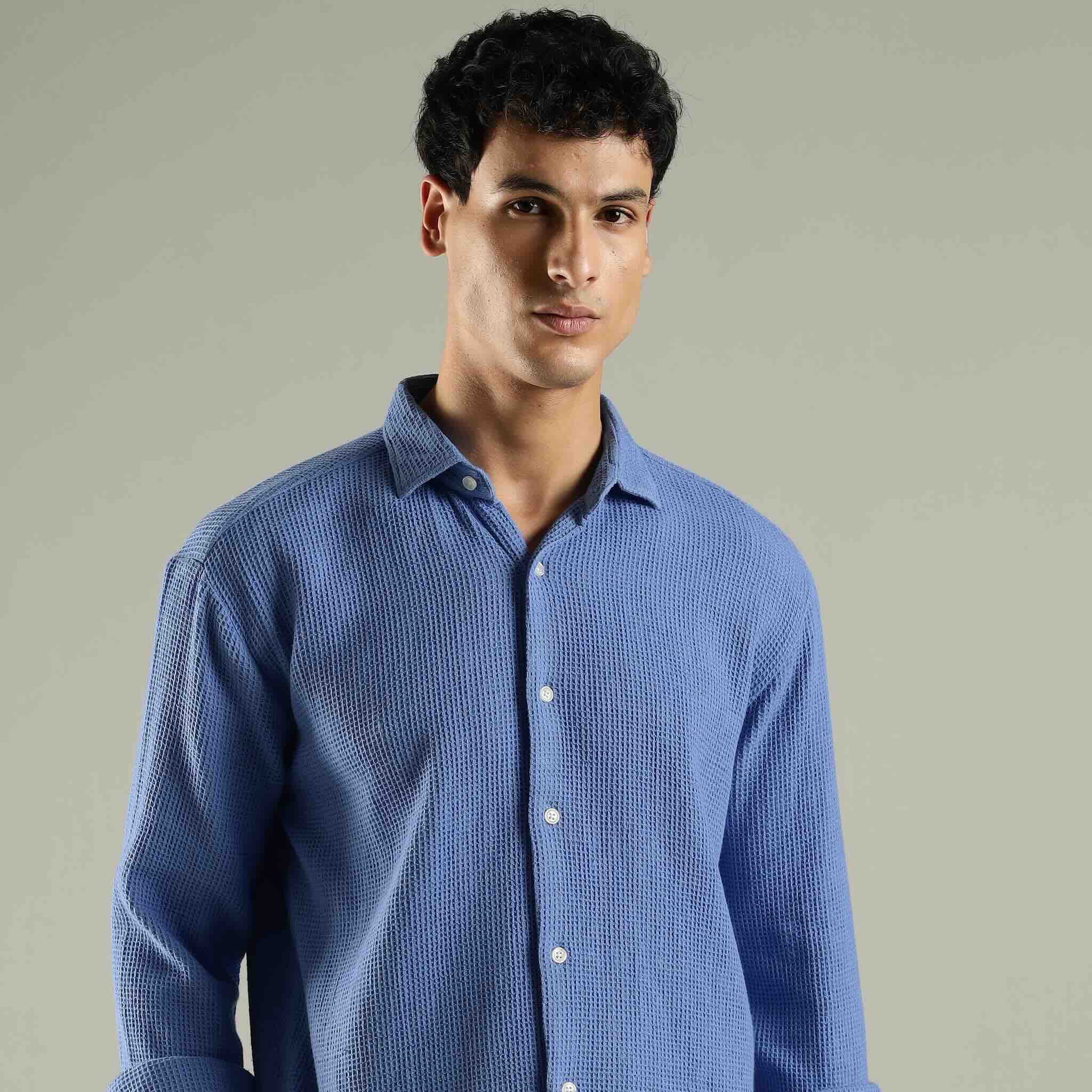 Man wearing a blue textured shirt against a plain background
