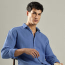 Man wearing a blue textured shirt against a gray background