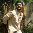 Man wearing sandstone shirt leaning against a tree in a natural setting