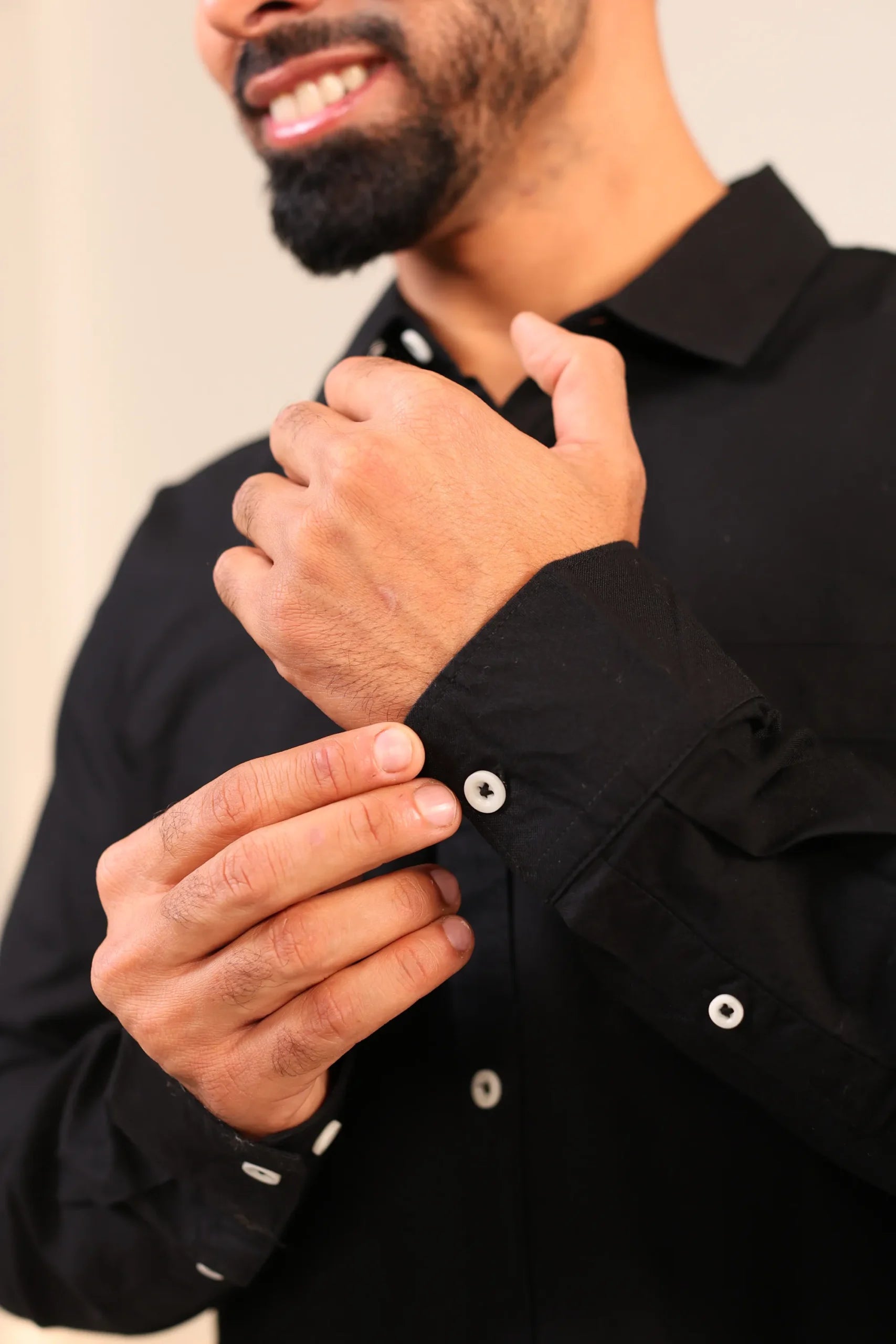 Close-up of black shirt cuff with man adjusting button.