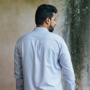 Man wearing a light blue shirt against a textured wall.