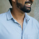 Man wearing a light blue shirt with a neutral background