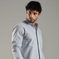 Man wearing a light blue shirt against a gray background