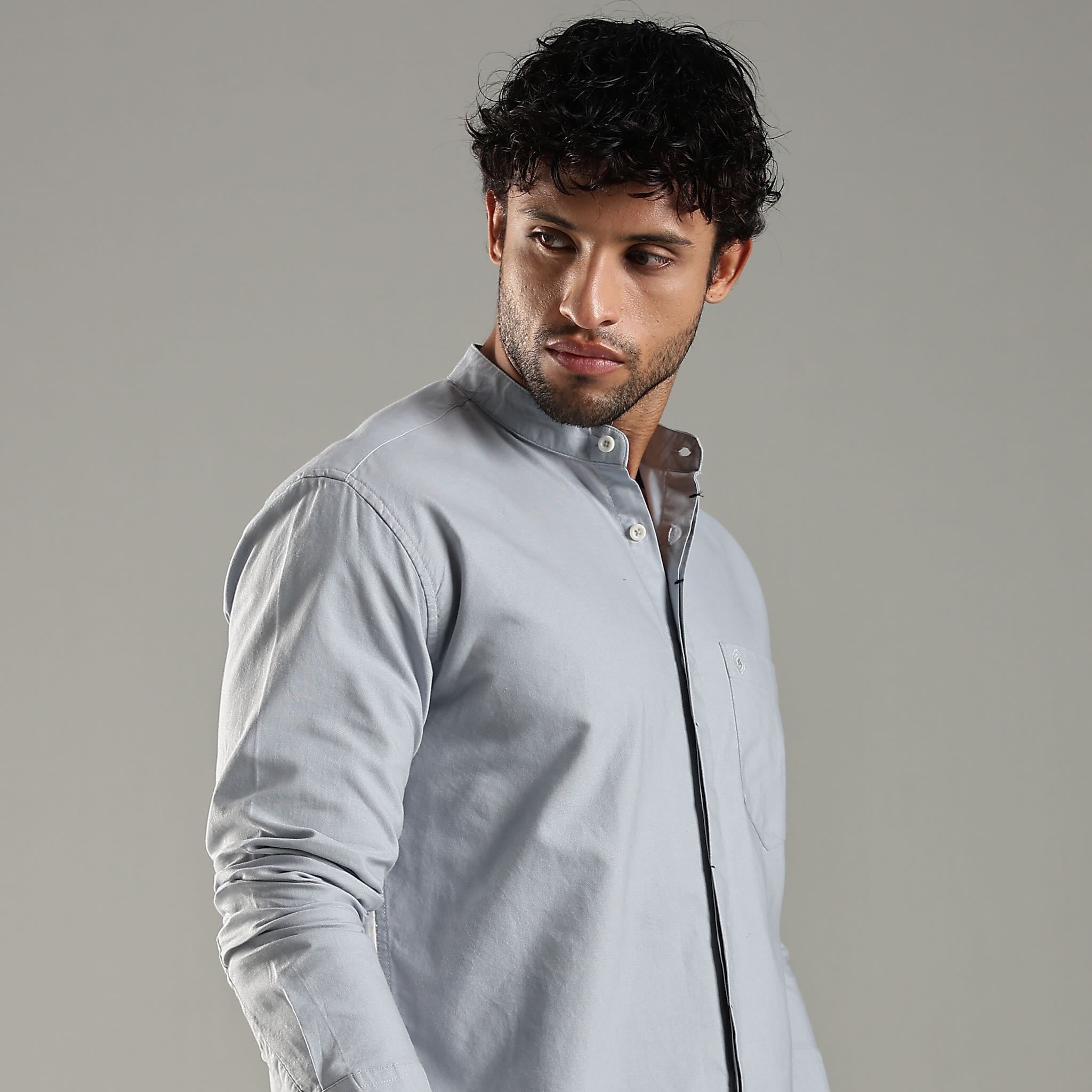 Man wearing a light blue shirt against a gray background