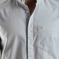Light blue button-up shirt with a pocket detail on a plain background