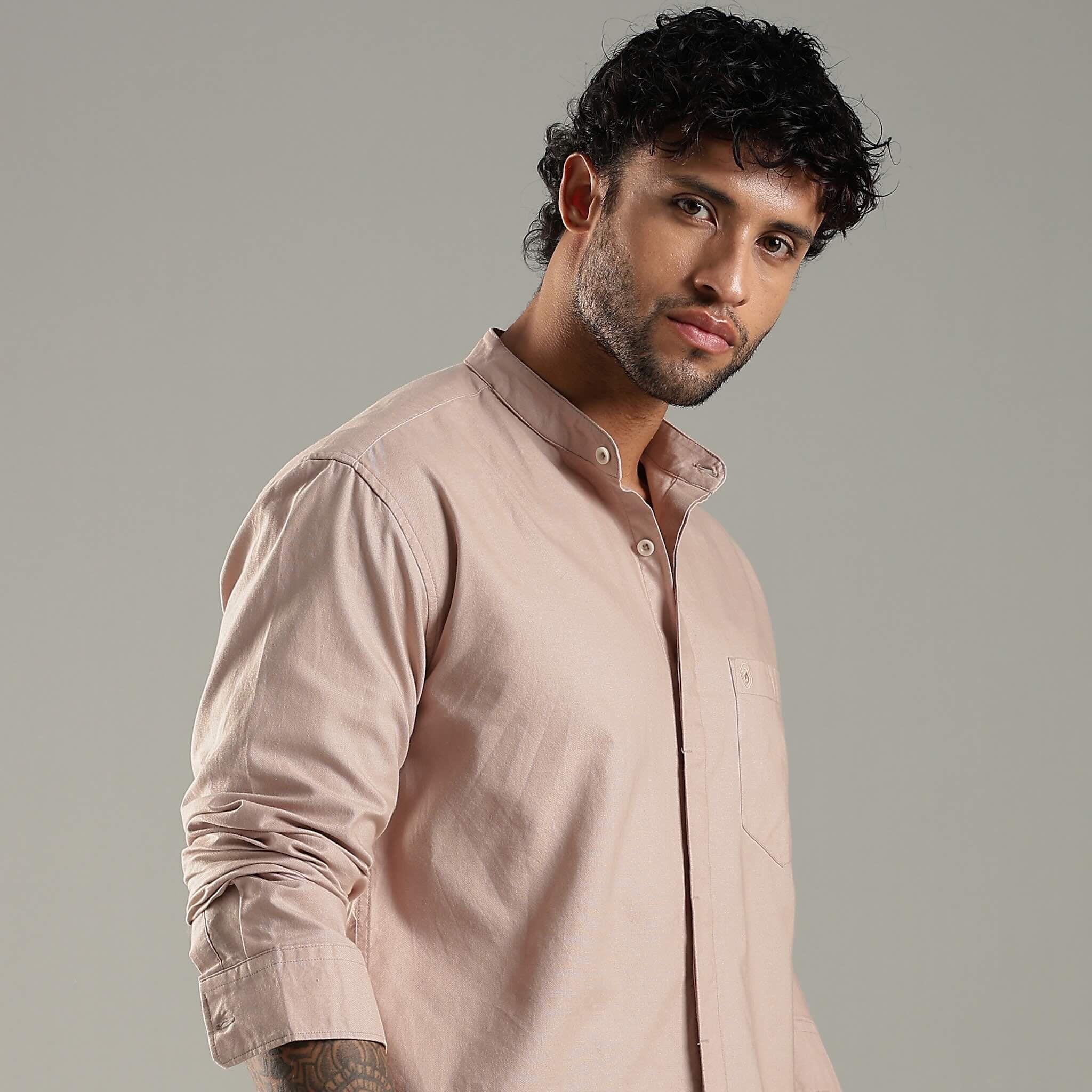 Man wearing a light brown shirt against a gray background