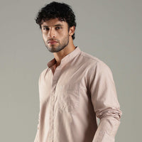 Man wearing a light pink shirt against a gray background