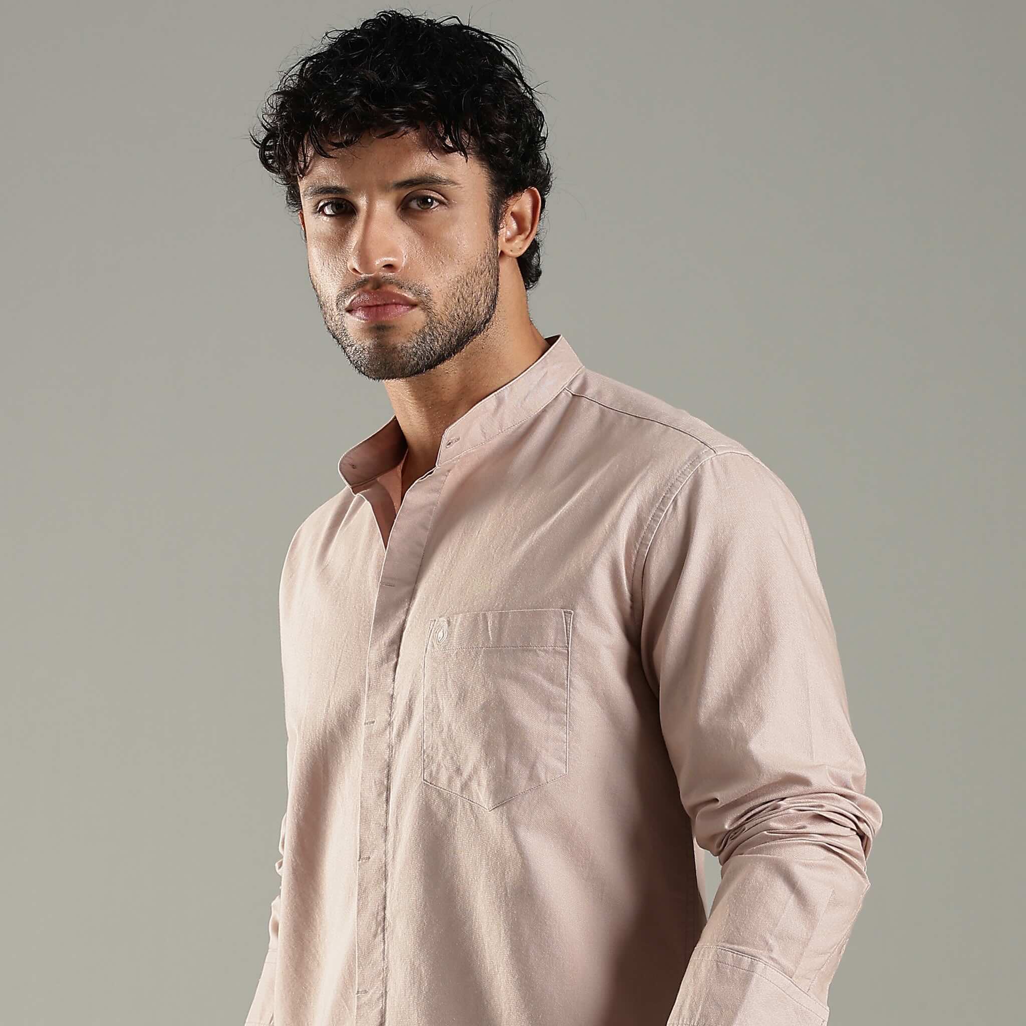 Man wearing a light pink shirt against a gray background