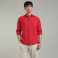 Man wearing a red linen shirt and beige pants against a gray background