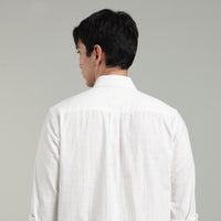 Man wearing a white hemp shirt and facing against a gray background