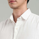 Close-up of a person wearing a white hemp shirt against a gray background