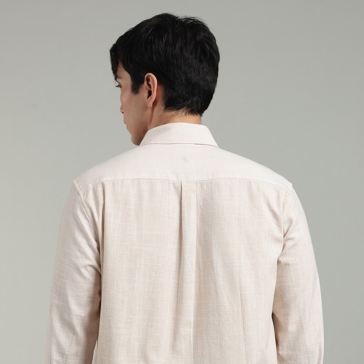 Man wearing a beige shirt against a gray background