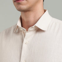 Close-up of a person wearing a light-colored shirt with a gray background