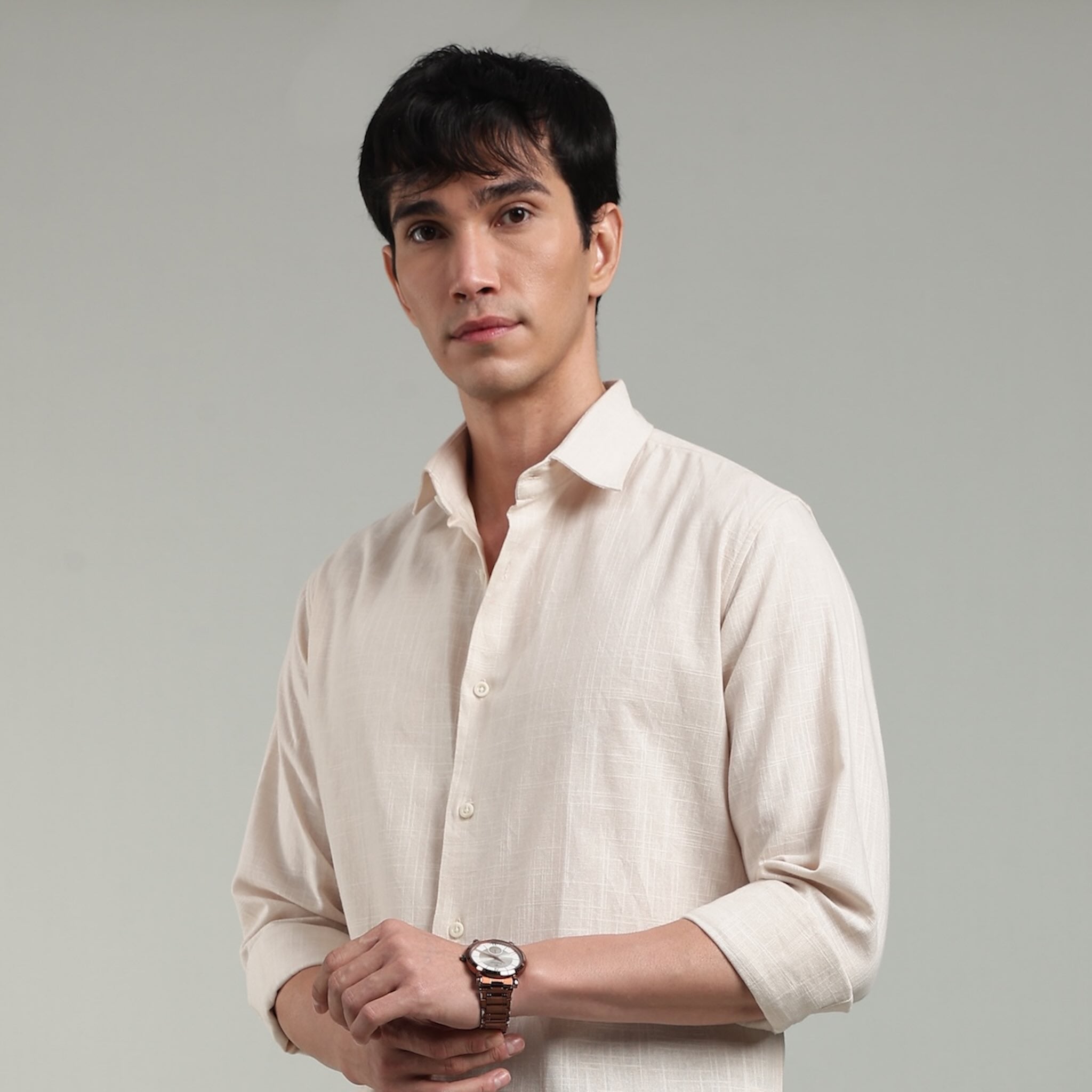 Man wearing a beige colored shirt against a plain background