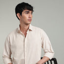 Man wearing a beige colored shirt against a plain background