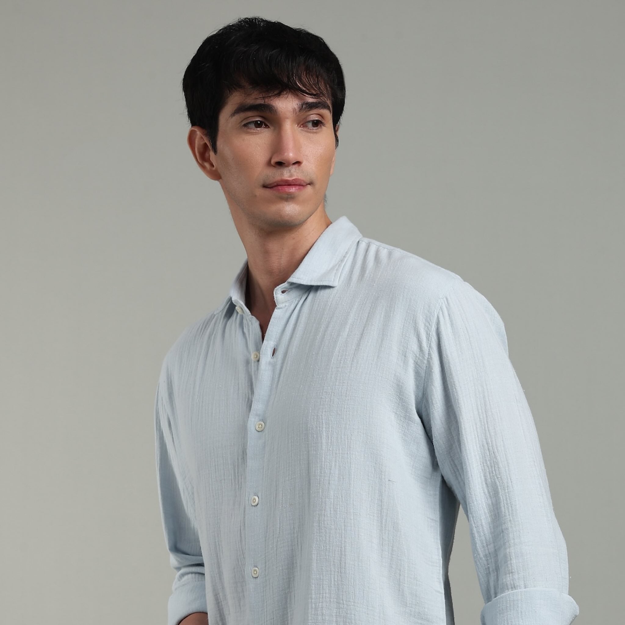 Man wearing a light blue shirt against a gray background