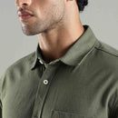 Close-up of a person wearing a green hemp shirt with a neutral background