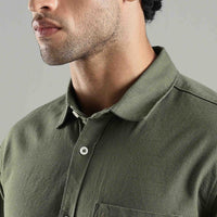 Close-up of a person wearing a green hemp shirt with a neutral background