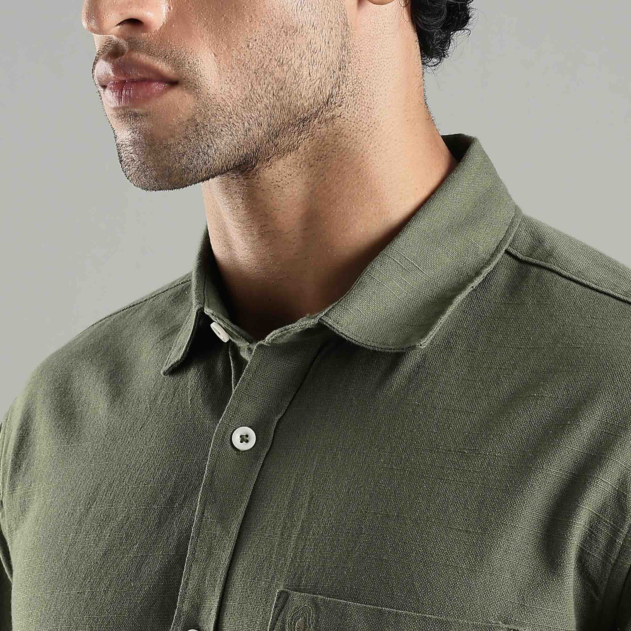 Close-up of a person wearing a green hemp shirt with a neutral background