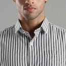 Close-up of a person wearing a black and white striped shirt against a gray background
