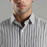 Close-up of a person wearing a black and white striped shirt against a gray background
