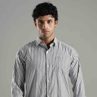 Man wearing a black and white striped shirt against a gray background

