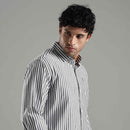 Man wearing a black and white striped shirt against a gray background