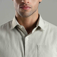 Close-up of a man wearing a light green button-up shirt against a gray background