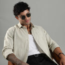 Man wearing sunglasses and a light green shirt against a gray background