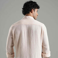 Man wearing a light pink textured shirt against a gray background