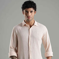 person wearing a textured light pink shirt with a neutral background