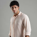 Man wearing a light pink textured shirt against a gray background