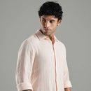 person wearing a textured light pink shirt with a neutral background