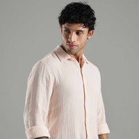 person wearing a textured light pink shirt with a neutral background
