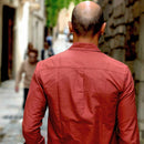 Man in a red shirt walking down a street with blurred background