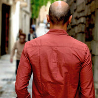 Man in a red shirt walking down a street with blurred background