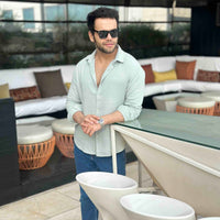 Man in light green shirt and sunglasses standing in a modern outdoor setting