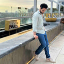 Man wearing light green shirt leaning on a railing with a cityscape background
