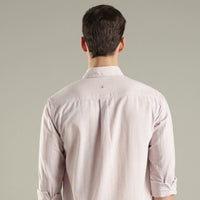 Man wearing a light pink hemp shirt from behind on a gray background