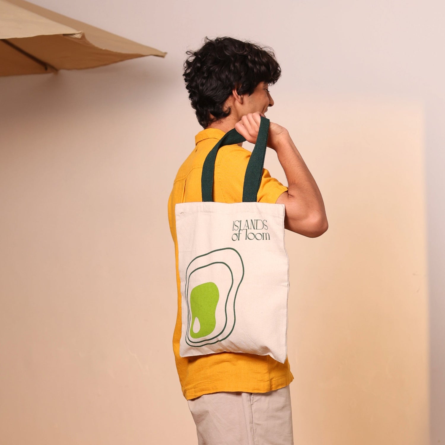 Person holding a tote bag with a logo on a plain background